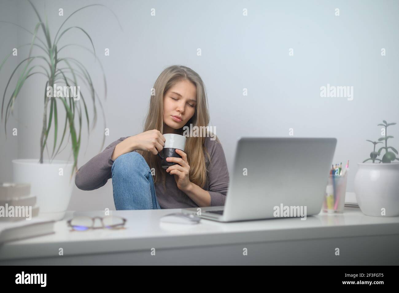 Une fille avec un ordinateur portable étudie dans une école en ligne. Arrière-plan de la salle blanche Banque D'Images