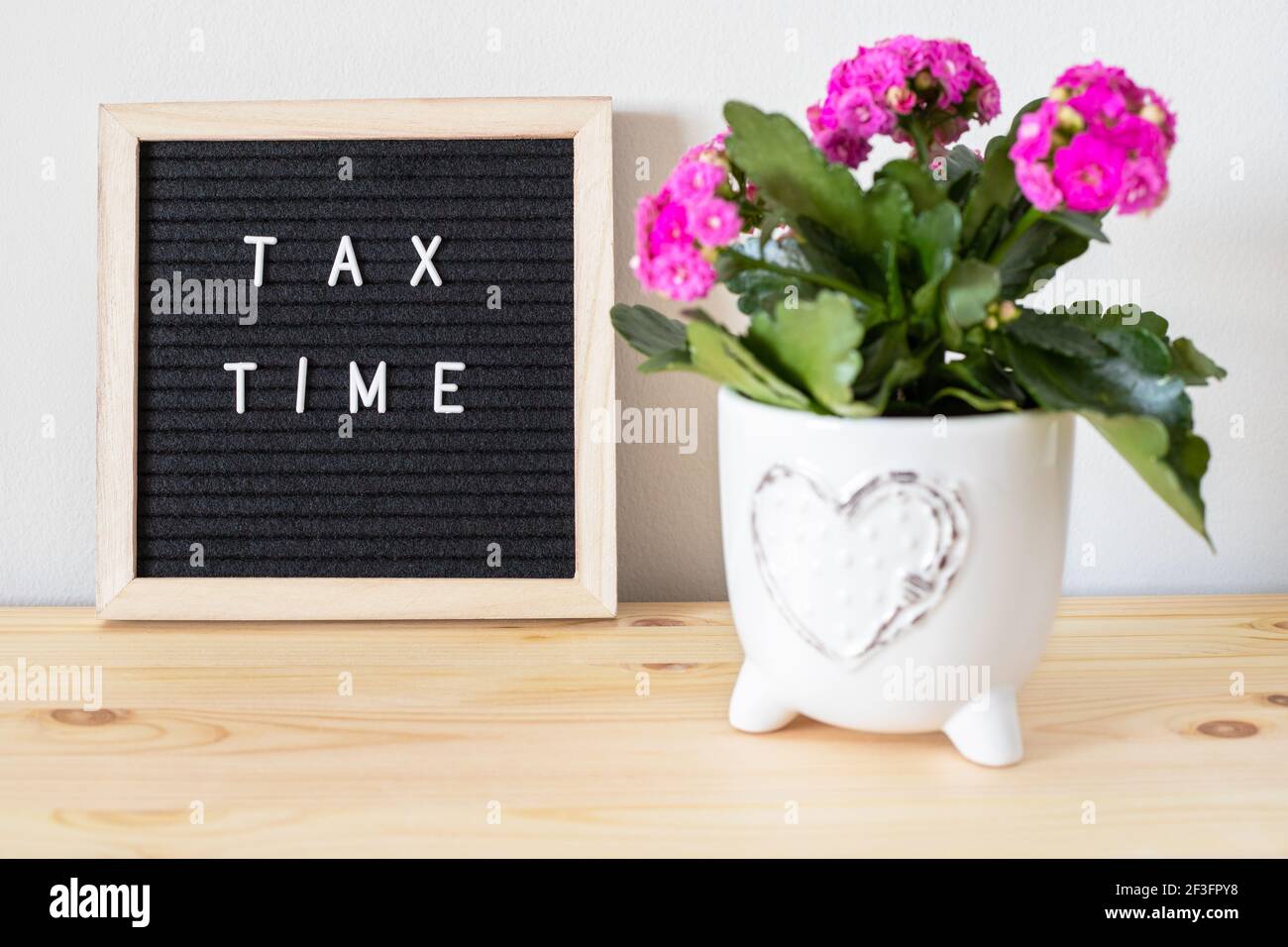 Tableau de lettres et pots de fleurs en feutre noir pour l'heure d'imposition sur la table. Concept de déclaration de revenus des entreprises. Banque D'Images