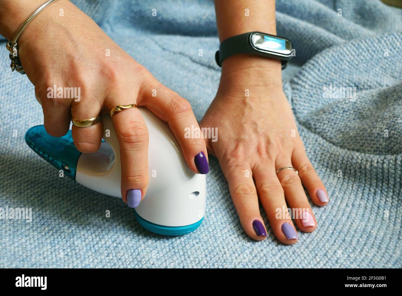 Dispositif sans fil pour le nettoyage des tissus tricotés contre les peluches. La femme retire les peluches du pull. Banque D'Images