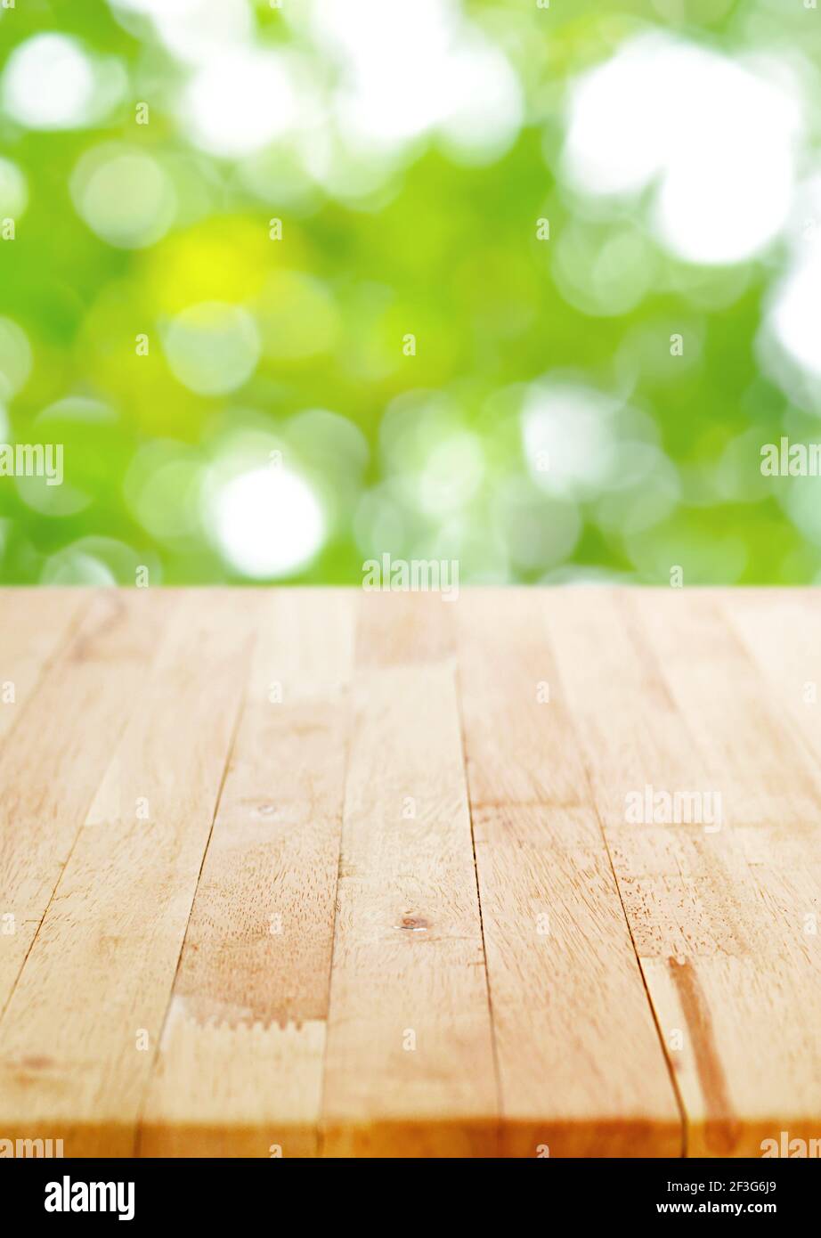 Plan de table en bois sur fond de bokeh vert flou, format d'affiche - peut être utilisé pour le montage ou l'affichage de vos produits Banque D'Images