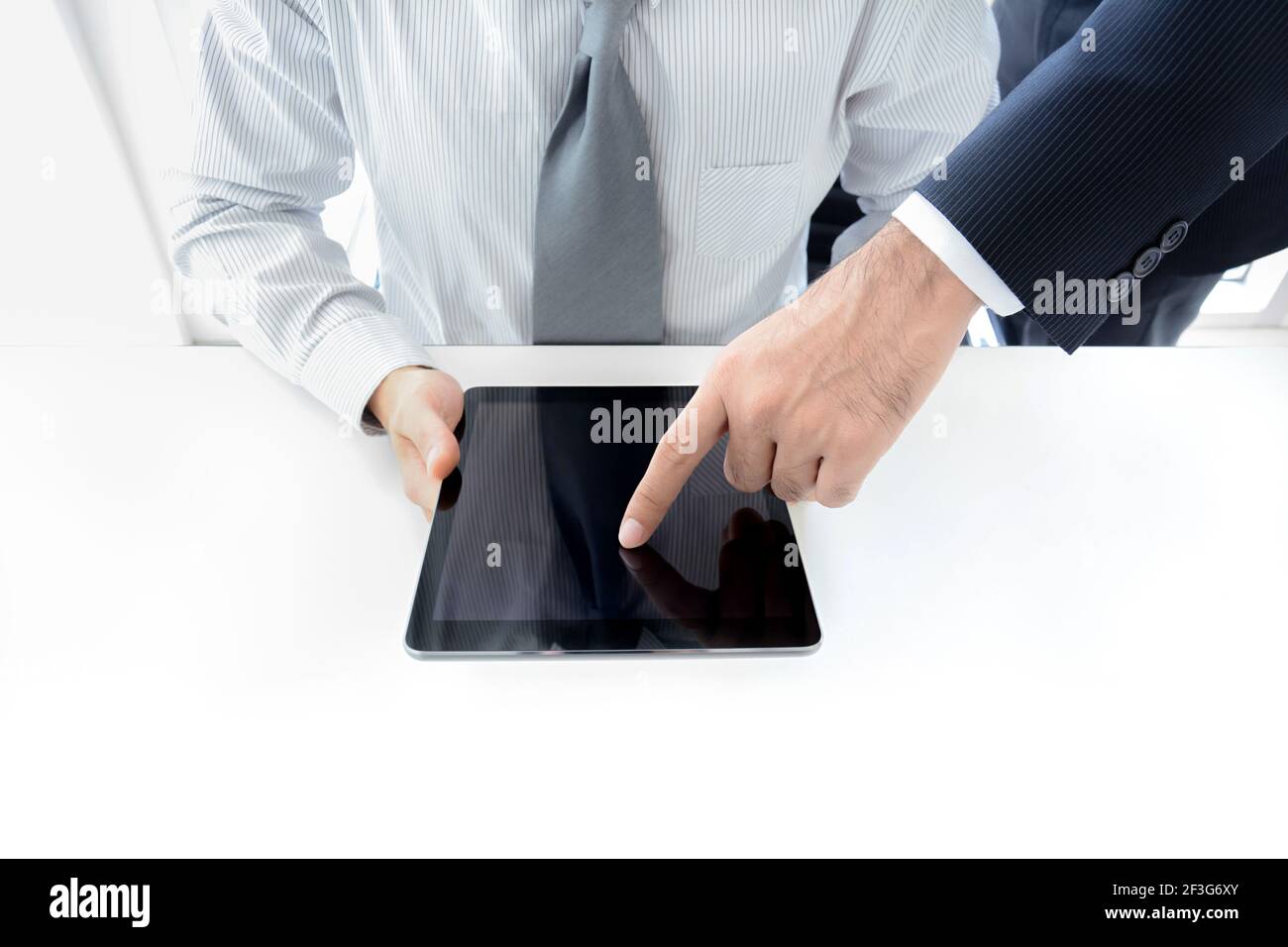 Deux hommes d'affaires utilisant une tablette avec une main touchant l'écran, concept de discussion d'affaires Banque D'Images