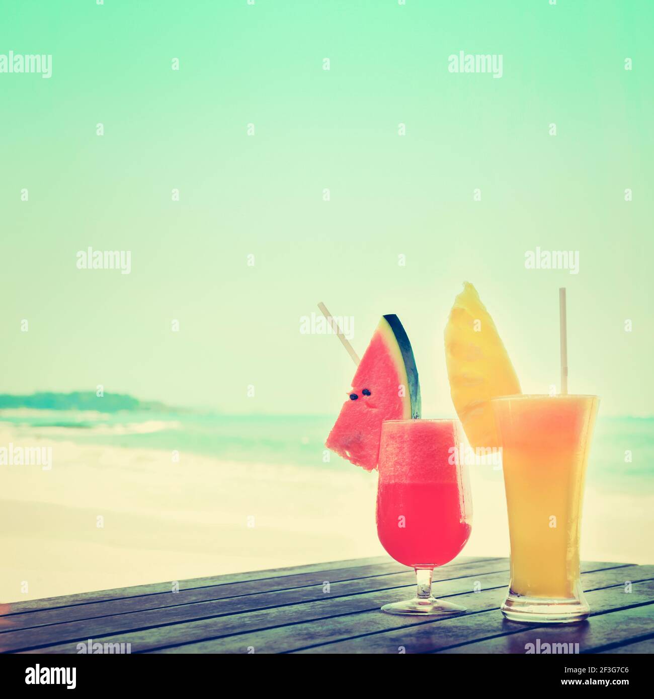 Smoothies aux fruits tropicaux colorés sur une table en bois à la plage, tons vintage Banque D'Images