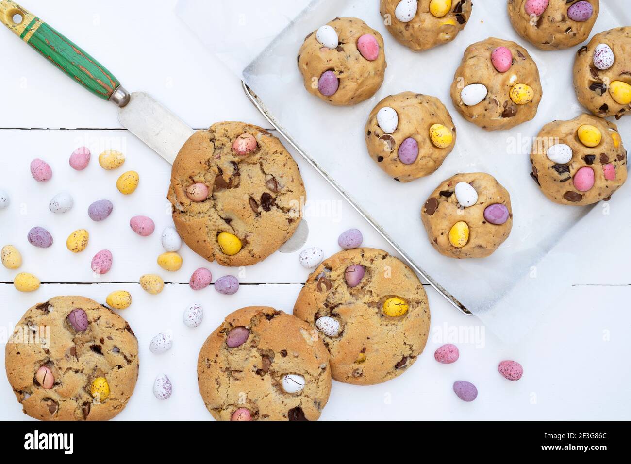 Petits biscuits aux œufs faits maison au chocolat et pâte à biscuits crue sur une plaque de cuisson Banque D'Images