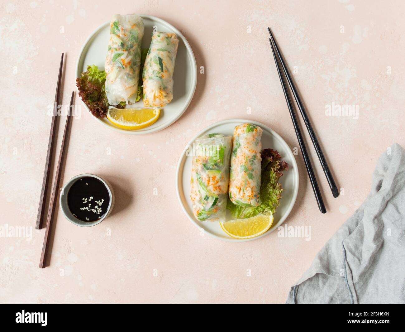 Rouleaux de printemps vietnamiens avec salade, sauce, crabe et nouilles sur les assiettes et saules dans un bol sur fond rose. Vue du dessus. Espace pour les copies Banque D'Images