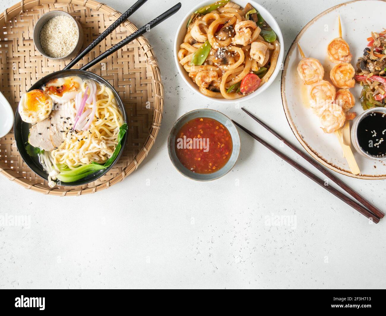 Set de cuisine asiatique - soupe de ramen, crevettes grillées, légumes sautés et udon avec fond blanc de fruits de mer. Vue de dessus. Copier l'espace. Pose à plat Banque D'Images