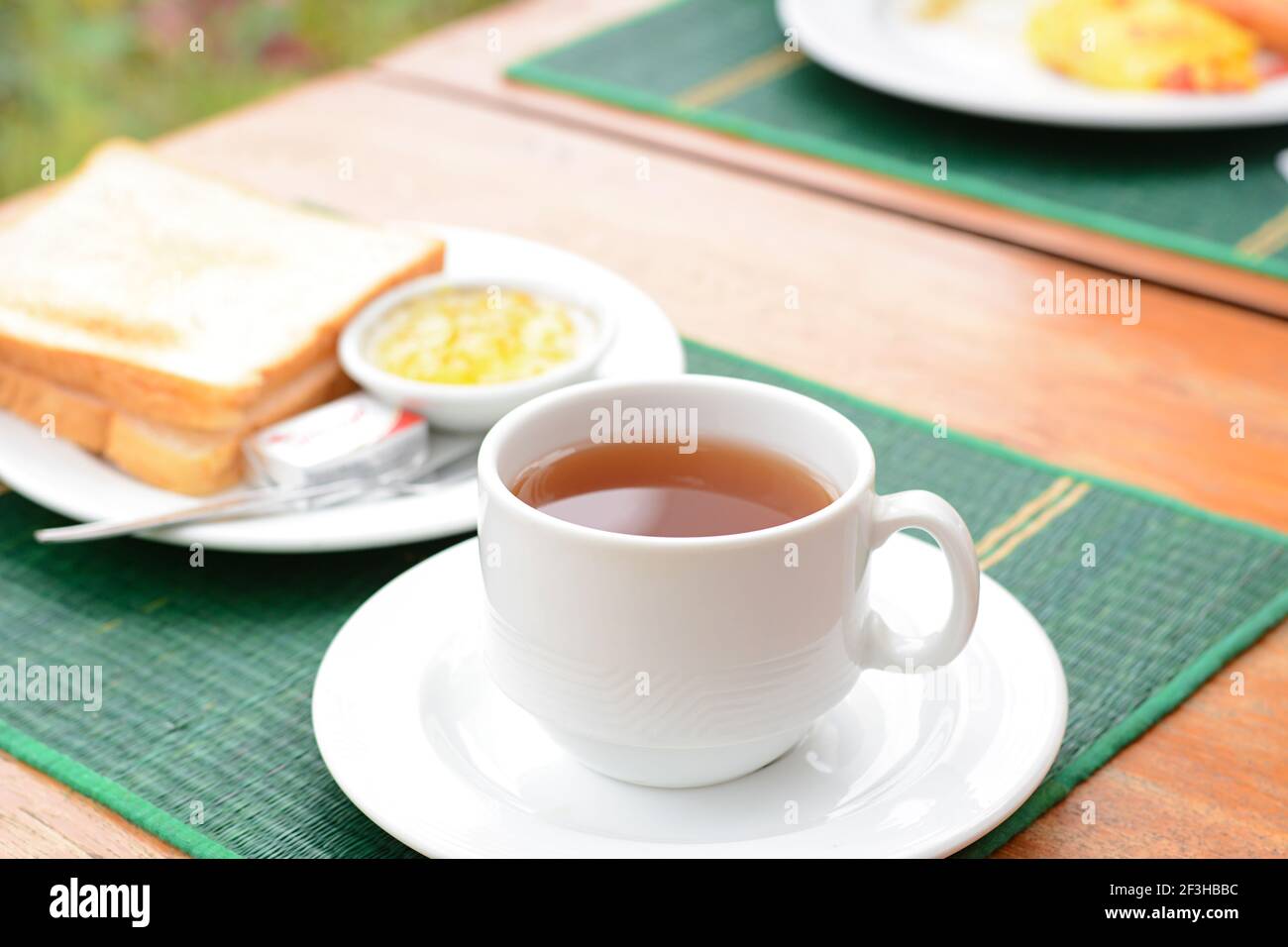 Thé chaud dans une tasse blanche avec pain grillé sur la table comme petit déjeuner Banque D'Images