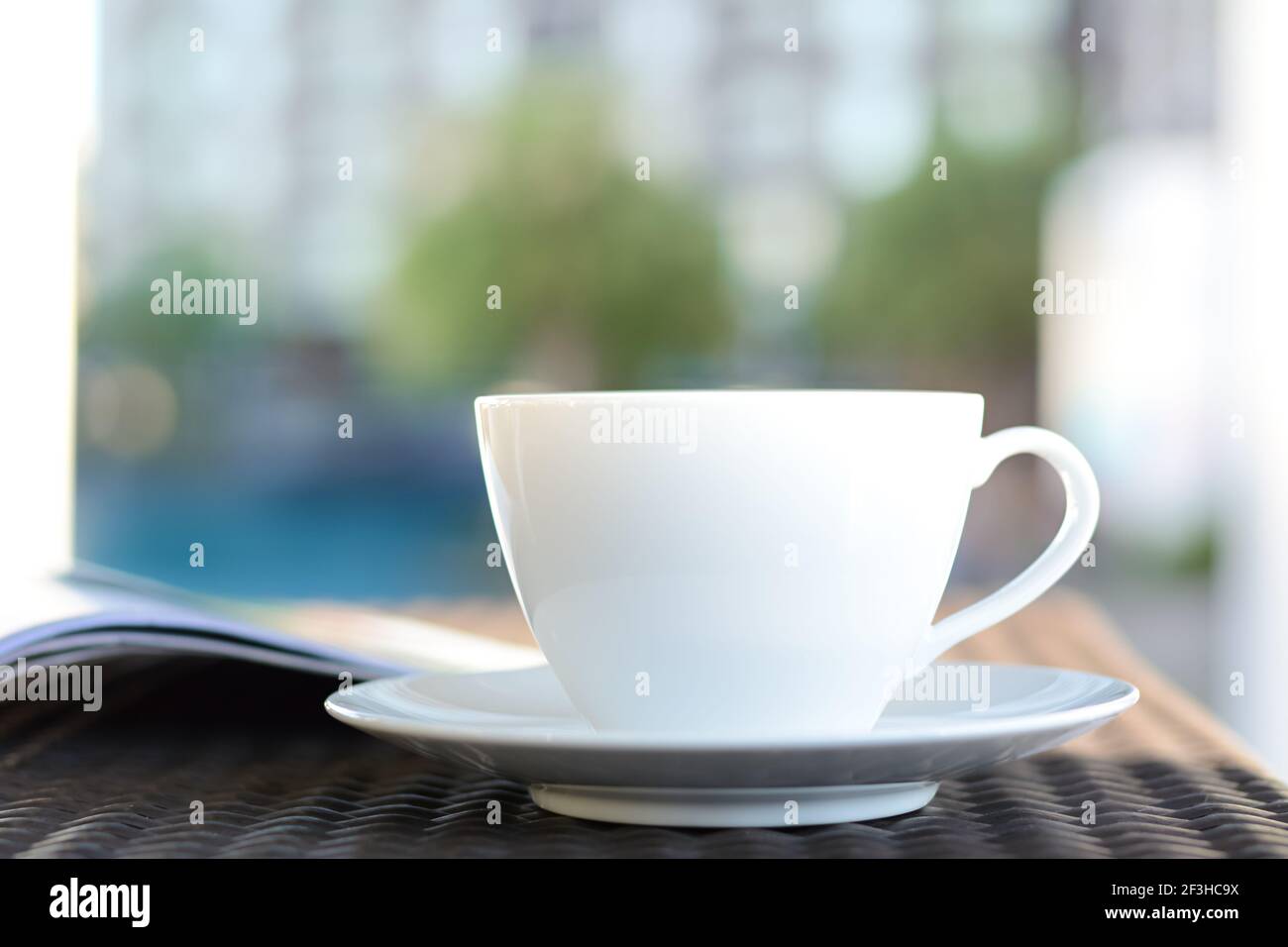 Tasse à café avec livre sur la table dans un bâtiment flou et de plantes vertes - détendez-vous dans l'hôtel ou concept d'hôtel Banque D'Images