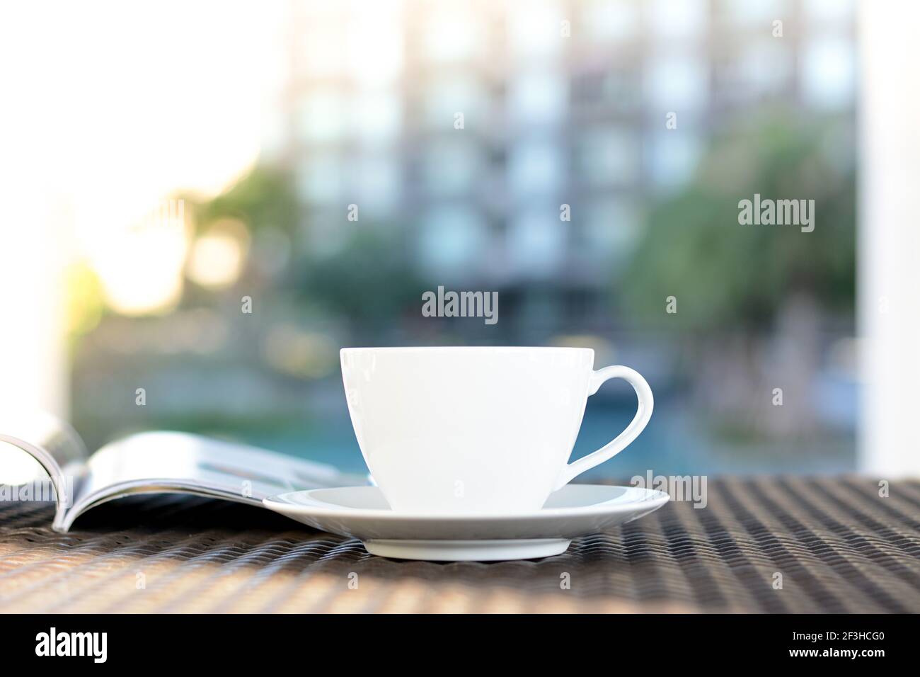 Tasse à café avec livre sur la table dans un bâtiment flou et de plantes vertes - détendez-vous dans l'hôtel ou concept d'hôtel Banque D'Images