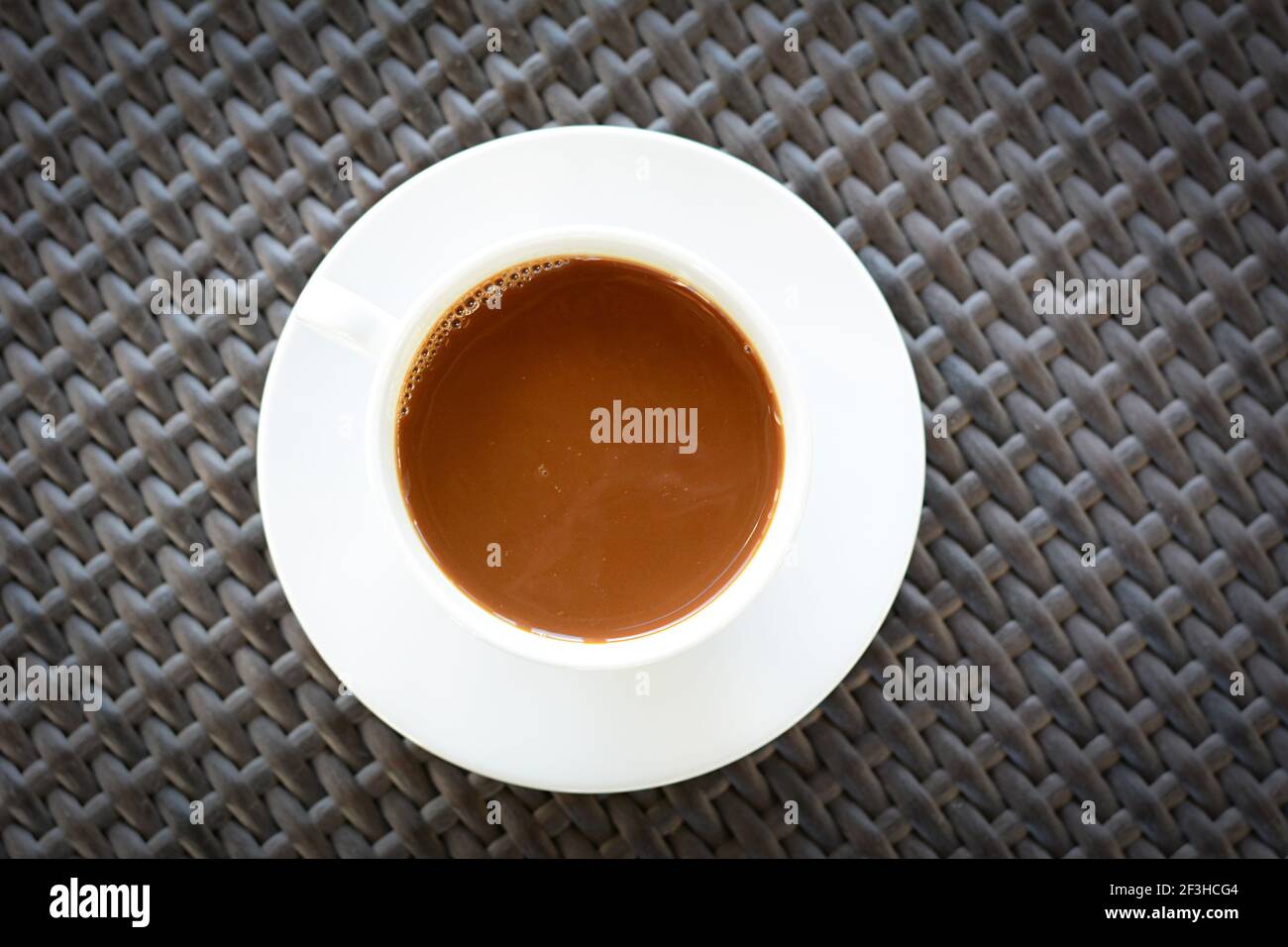 Une tasse de café sur une table en osier brun Banque D'Images