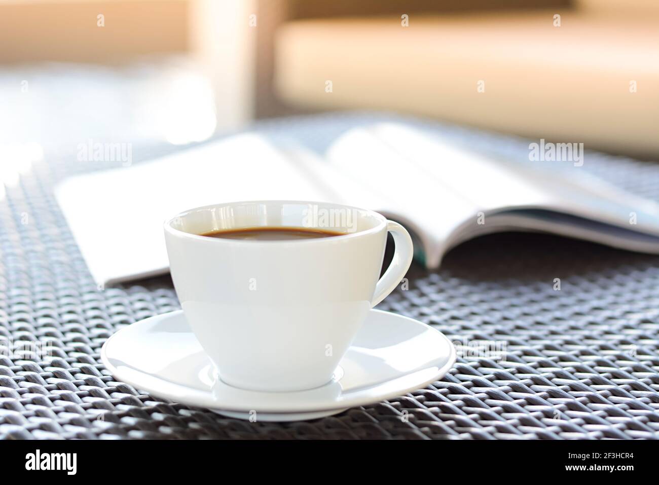 Tasse à café avec livre sur table en osier brun Banque D'Images