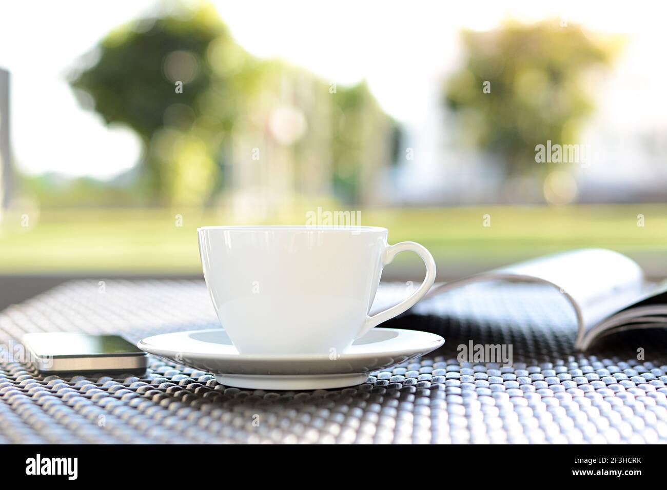 Tasse à café avec livre sur fond de nature vert flou - concept de détente Banque D'Images