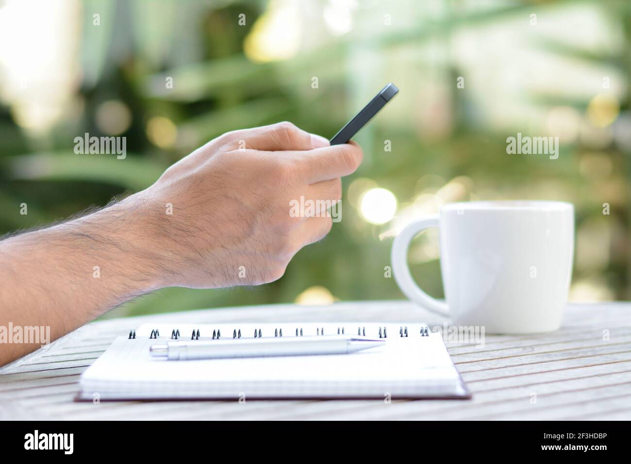 Main à l'aide d'un smartphone avec une tasse à café et un ordinateur portable la table - main focalisée Banque D'Images