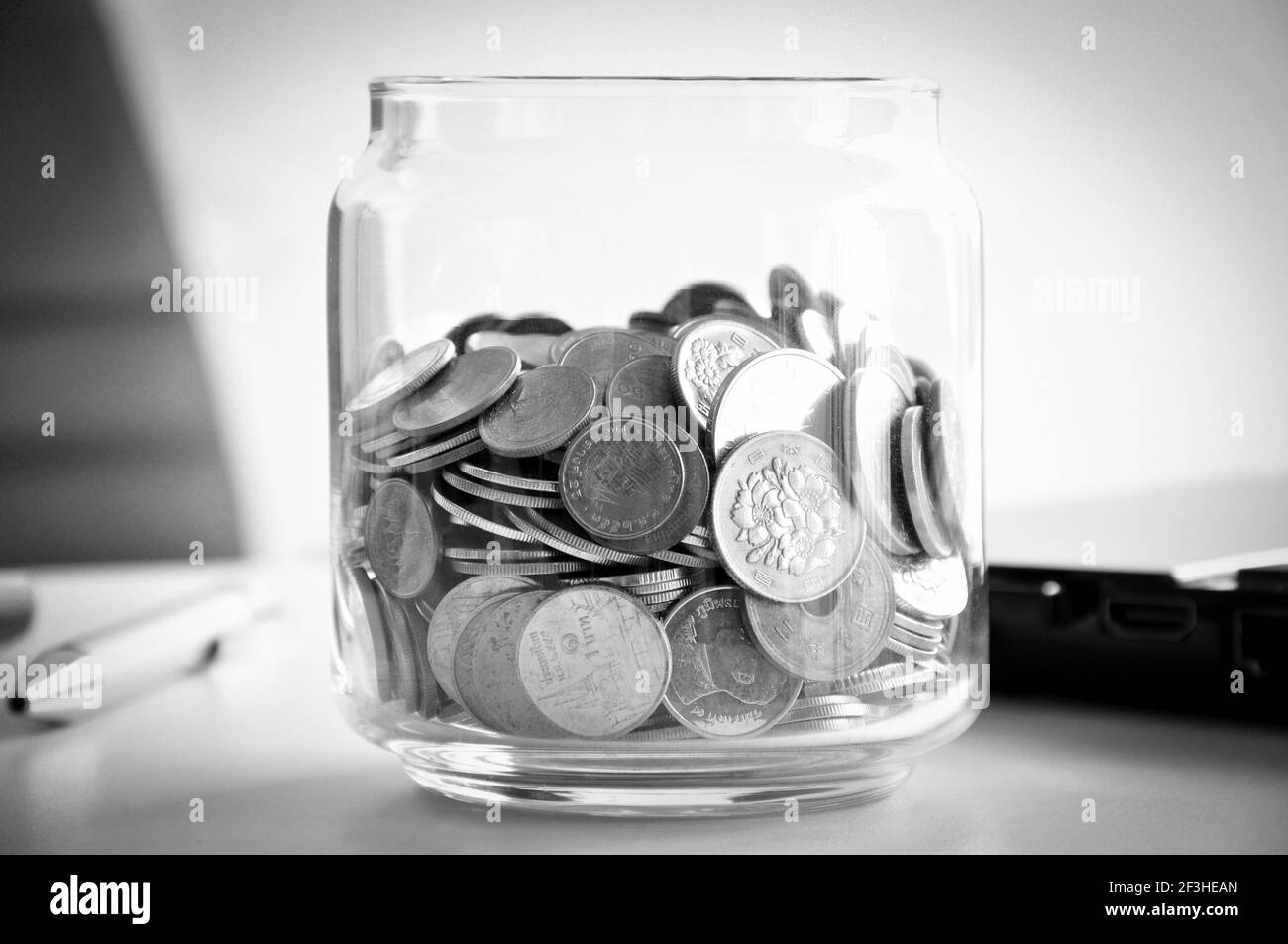 Pièces de monnaie dans le pot en verre, mélange asiatique multi-devises - effet monochrome Banque D'Images