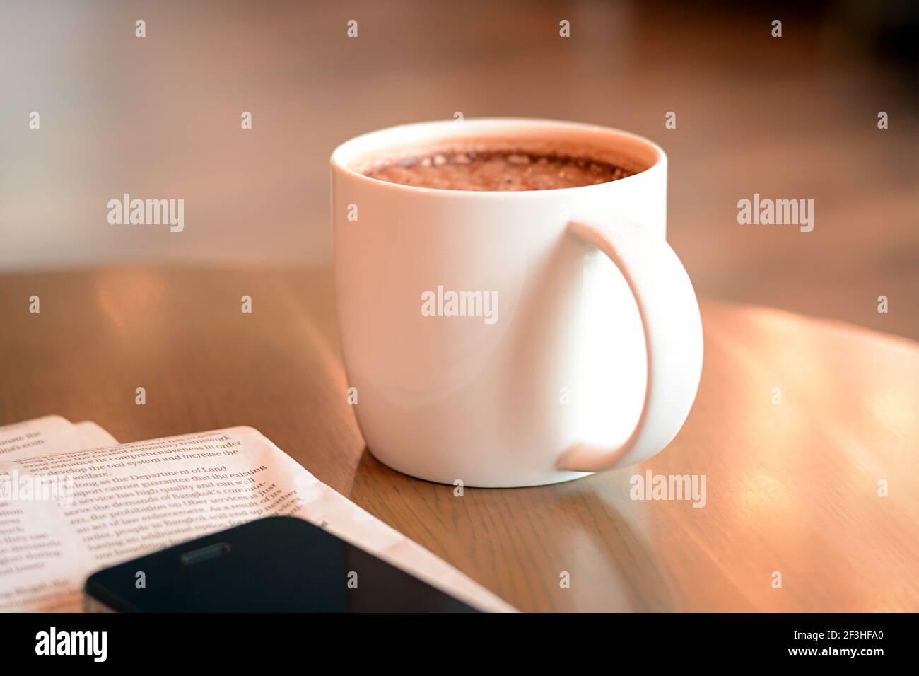 Tasse de chocolat chaud sur la table avec journal & téléphone portable à côté Banque D'Images