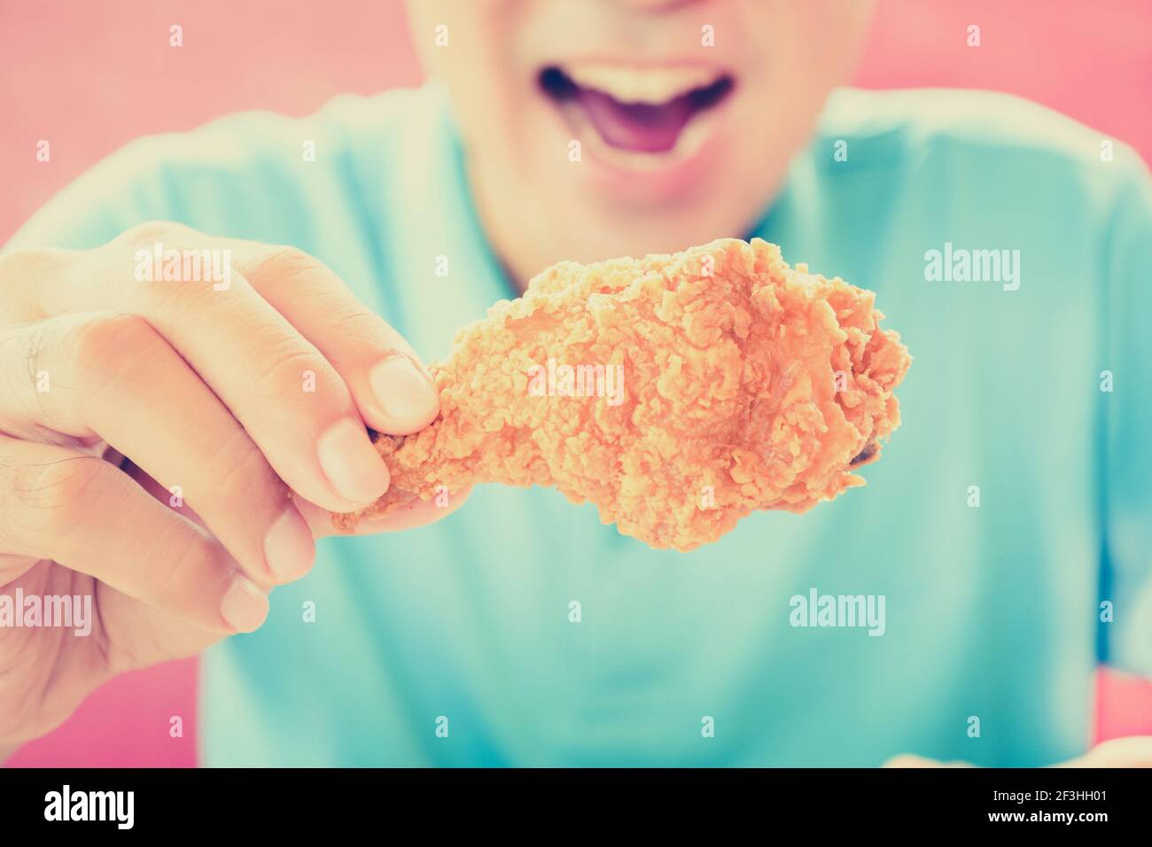 Un homme à la bouche ouverte sur le point de manger frits cuisse de poulet ou bâton de poulet - effet de couleur de style vintage Banque D'Images