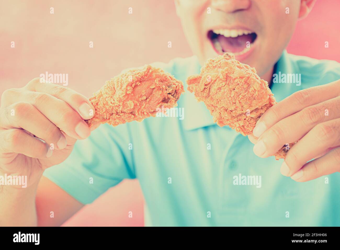 Un homme à la bouche ouverte sur le point de manger frits cuisses de poulet ou pilons - effet de couleur de style rétro Banque D'Images