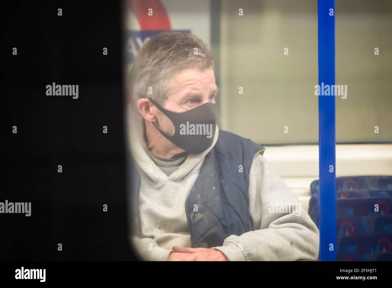 Londres, Royaume-Uni - 26 février 2021 - UN homme portant un masque facial lors d'un voyage dans le métro de Londres pendant la pandémie Covid-19 Banque D'Images