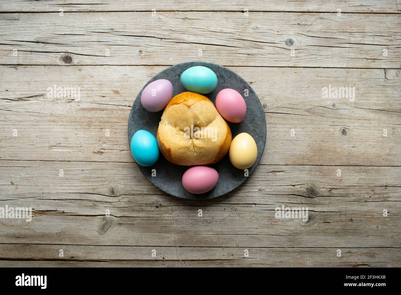 petit pain de pâques pinze avec quelques œufs de pâques colorés arrière-plan en bois Banque D'Images