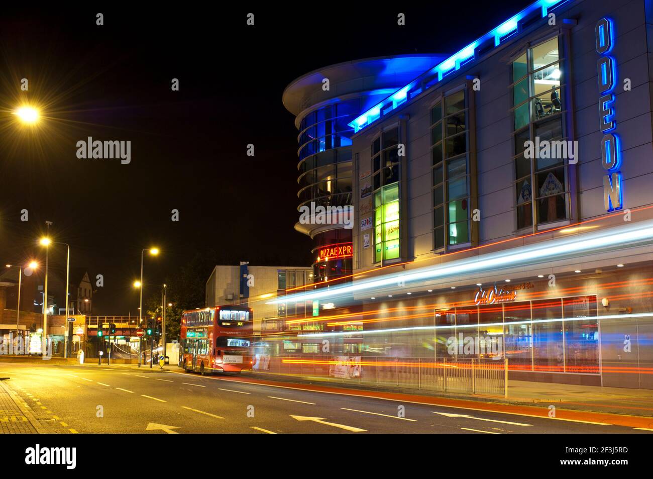 Vue de la Rotonde Shopping Centre, à Kingston, Surrey, dans la nuit avec un bus à double étage passant de quitter les sentiers de lumière. Banque D'Images