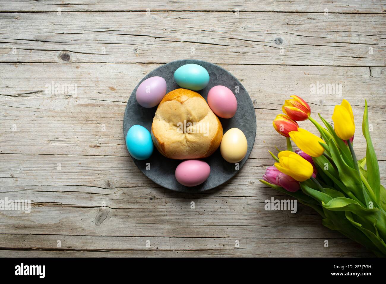 pinze de pain de pâques avec quelques œufs de pâques colorés sur bois arrière-plan et fleurs Banque D'Images