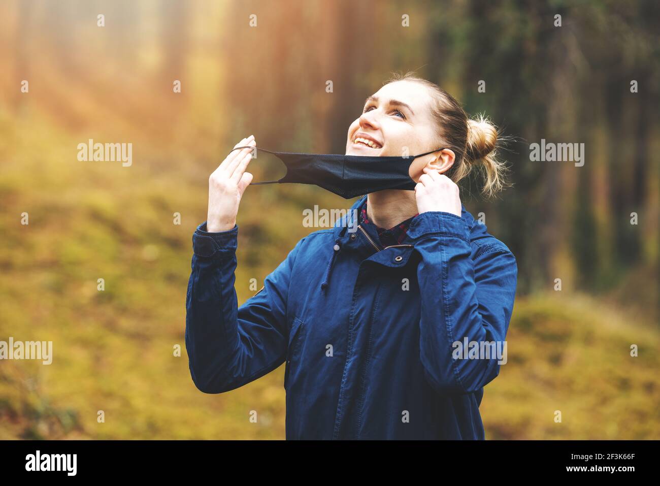 femme heureuse enlever le masque facial et respirer de l'air frais dans le parc. fin de pandémie, concept de vie normale Banque D'Images