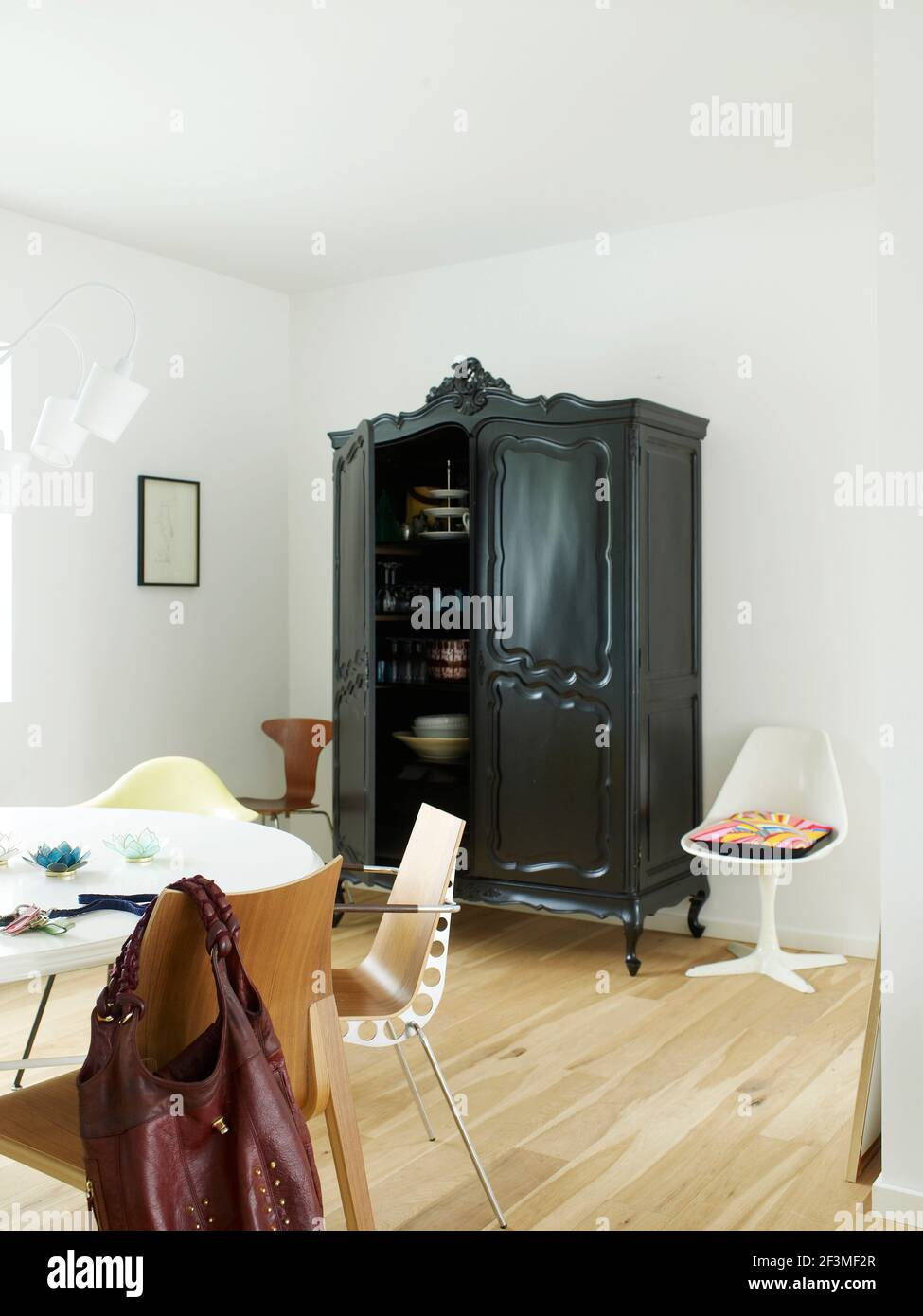 Table ronde, chaises et armoire noire dans une pièce blanche avec parquet dans une maison résidentielle, Danemark Banque D'Images