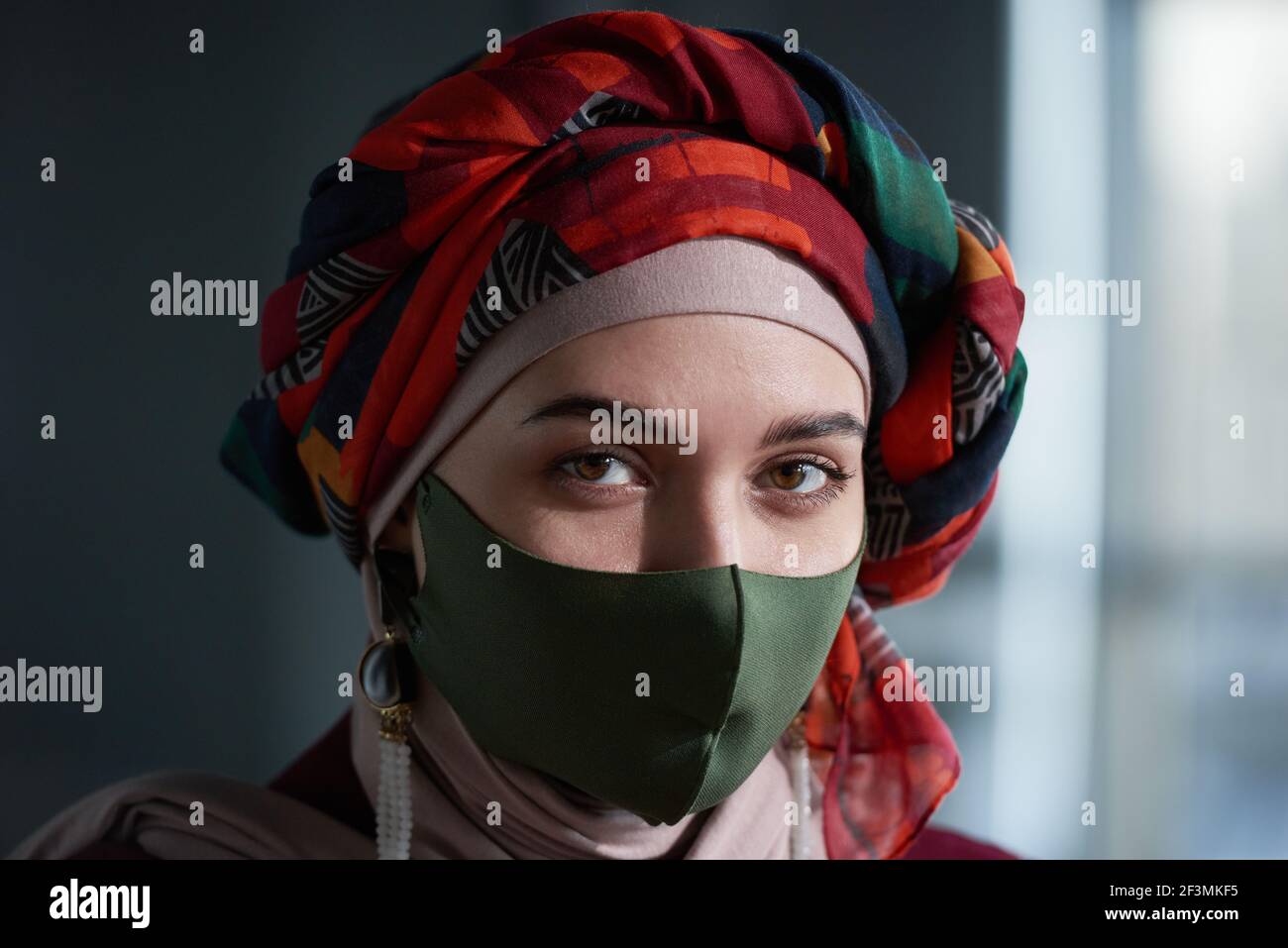 Portrait d'une femme musulmane dans un magnifique foulard sur la tête et masque de protection regardant l'appareil photo Banque D'Images