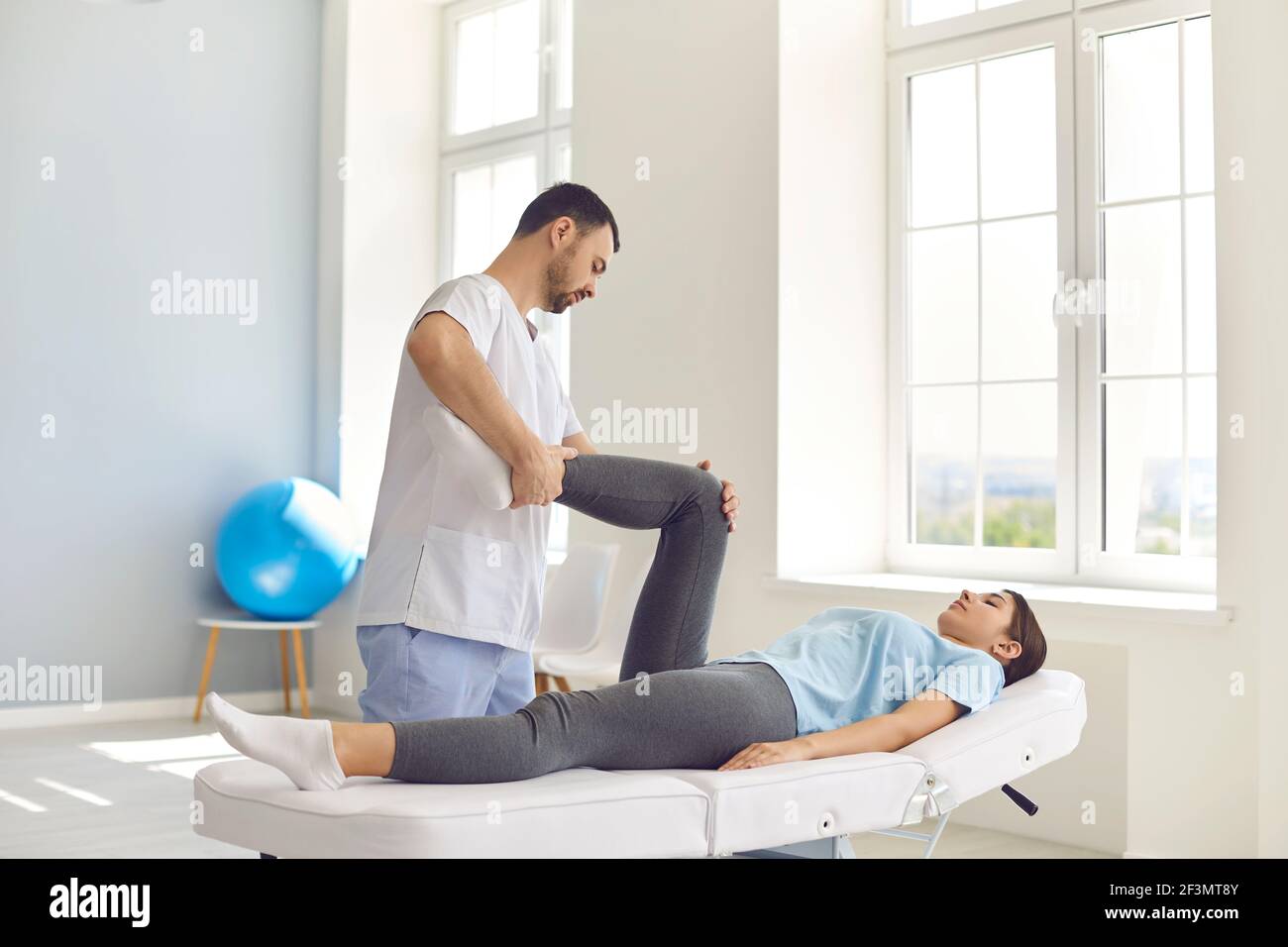 Jeune homme ostéopathe contrôlant les articulations de la femme couchée patients jambes Banque D'Images