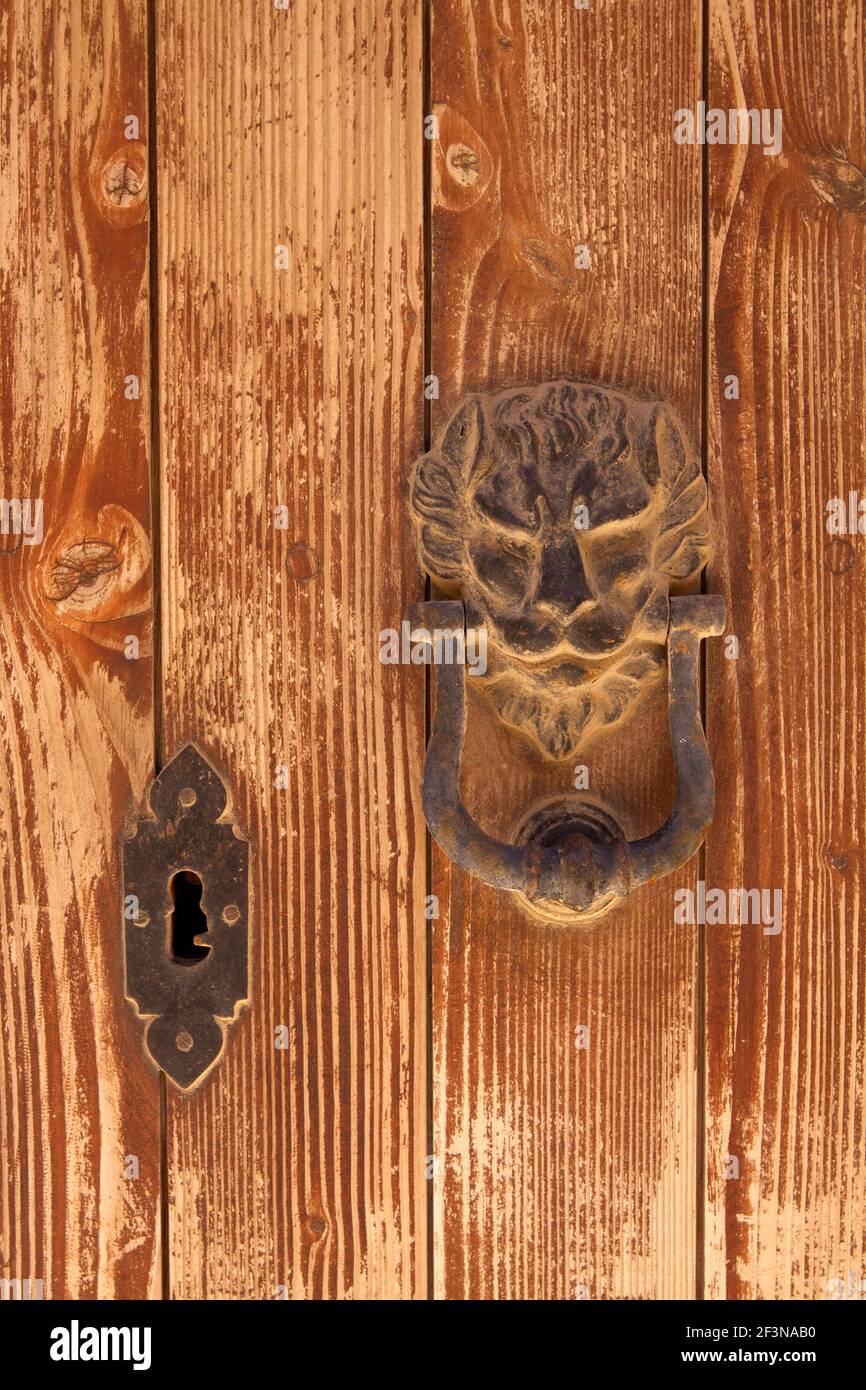 Porte-clé en fer poussiéreux en forme de tête de lions avec serrure sur une porte en bois « en dévêtu » dans la Citta Vecchia de Mdina, ou la vieille ville. Banque D'Images