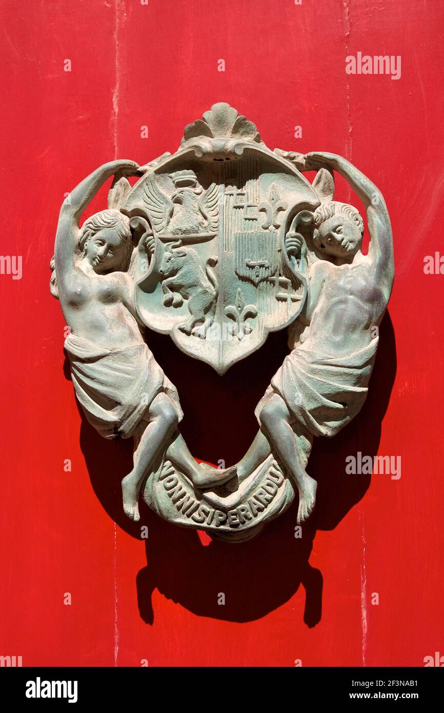 Heurtoir en bronze avec emblème familial et les nymphes sur une porte peinte en rouge Città Vecchia de Mdina. Banque D'Images