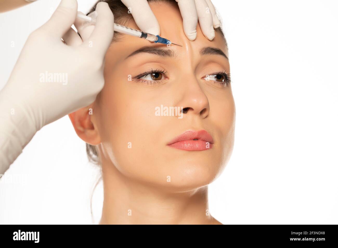 Portrait d'une jeune belle femme sur un visage de remplissage procédure d'injection sur fond blanc Banque D'Images