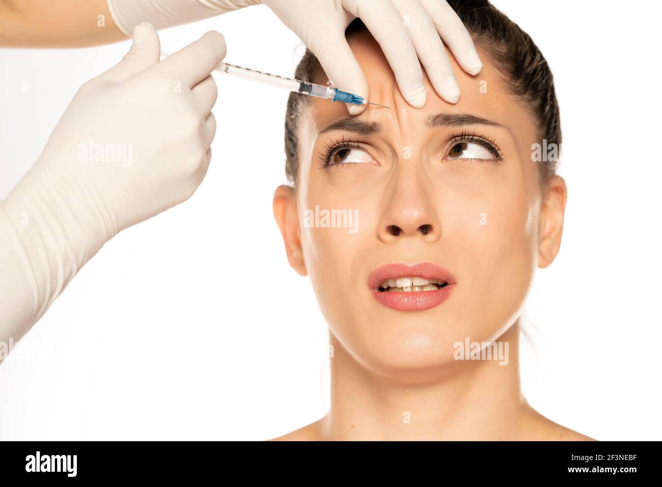 Portrait d'une jeune femme effrayée sur une garniture de faace procédure d'injection sur fond blanc Banque D'Images