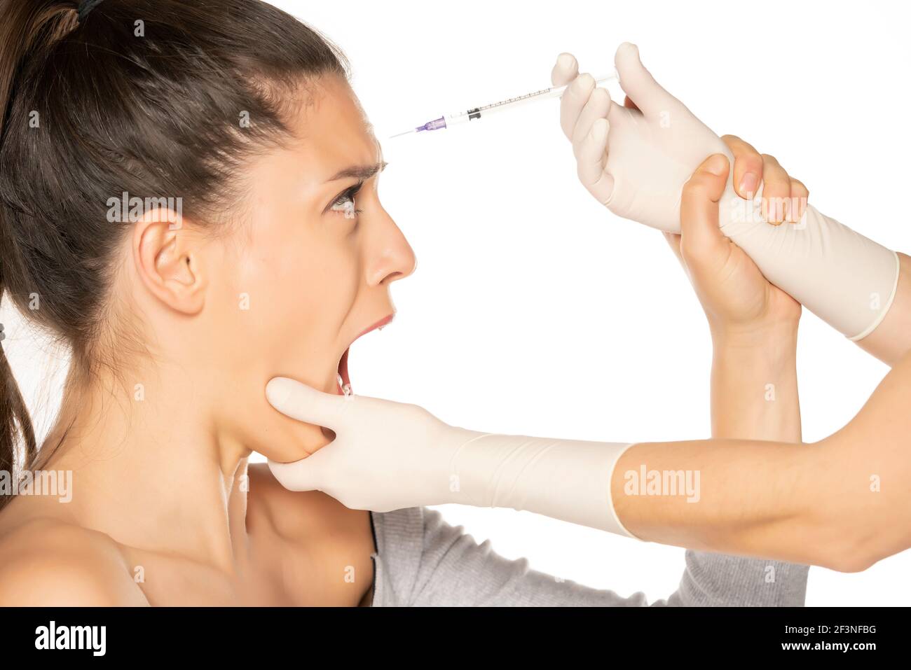 Portrait d'une jeune femme effrayée sur une garniture de faace procédure d'injection sur fond blanc Banque D'Images