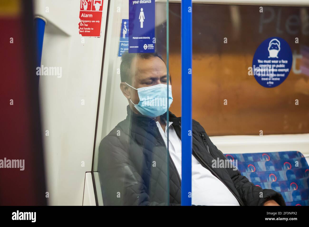 Londres, Royaume-Uni - 26 février 2021 - UN homme portant un masque facial lors d'un voyage dans le métro de Londres pendant la pandémie Covid-19 Banque D'Images