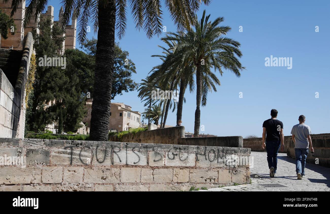 Palma, Espagne. 17 mars 2021. Deux hommes marchent devant un graffiti qui dit, 'touristes Rentre à la maison.' Credit: Clara Margais/dpa/Alay Live News Banque D'Images