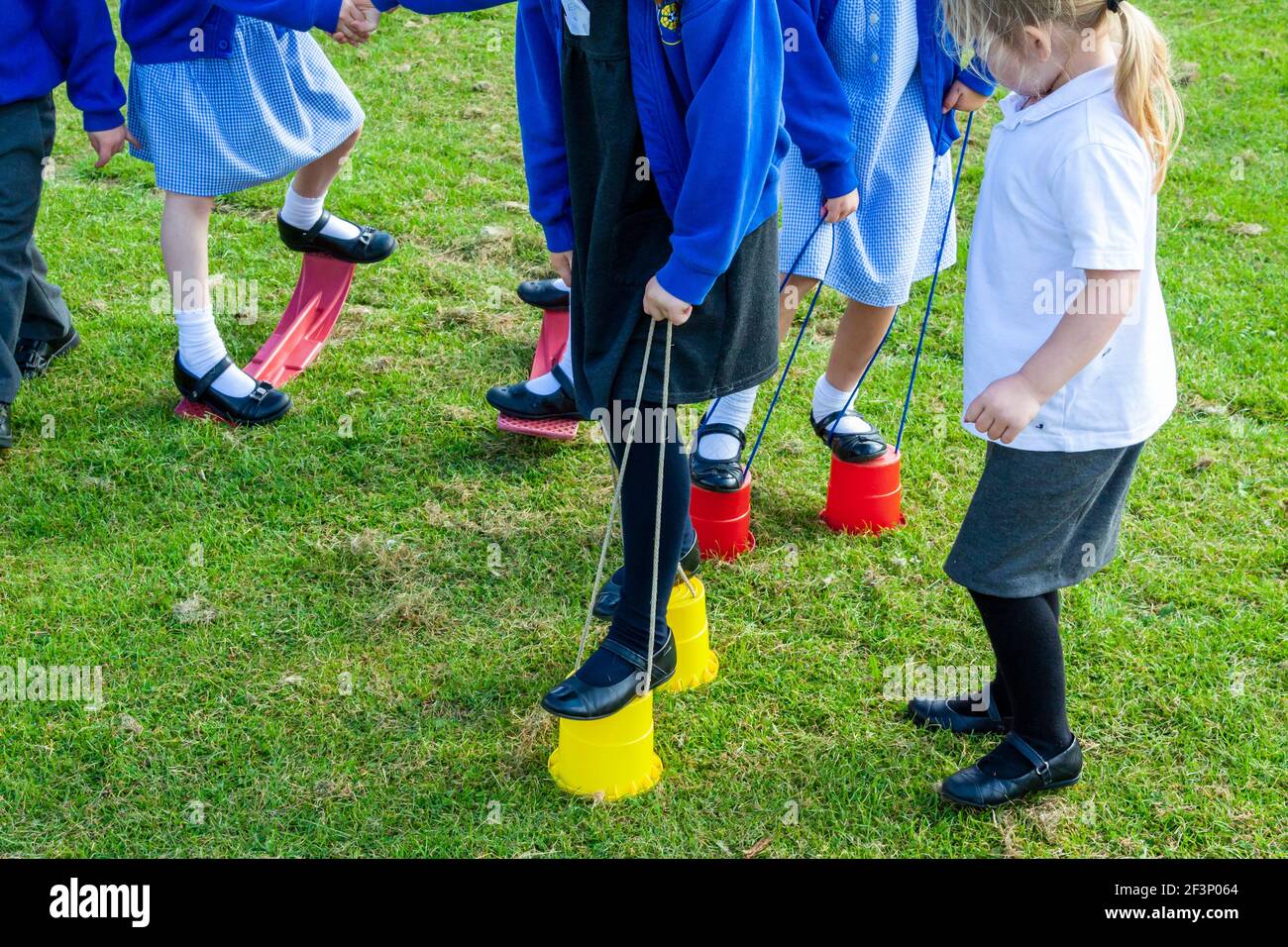 Les enfants de l'école primaire jouant sur des pilotis à l'extérieur dans une aire de jeux de l'école pendant une pause des leçons. Banque D'Images