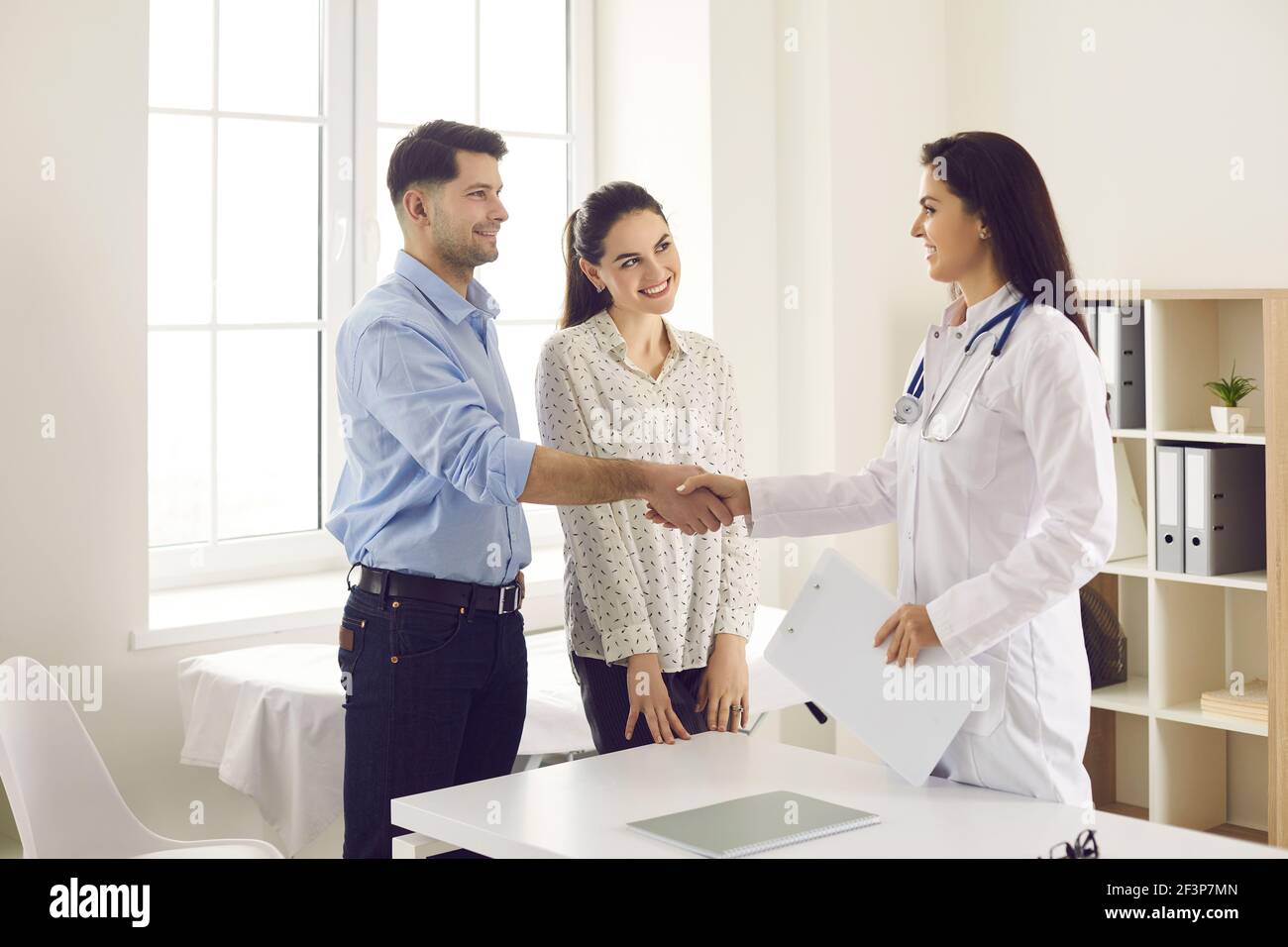 Un couple marié secoue les mains d'une gynécologue tout en se familiarisant. Banque D'Images