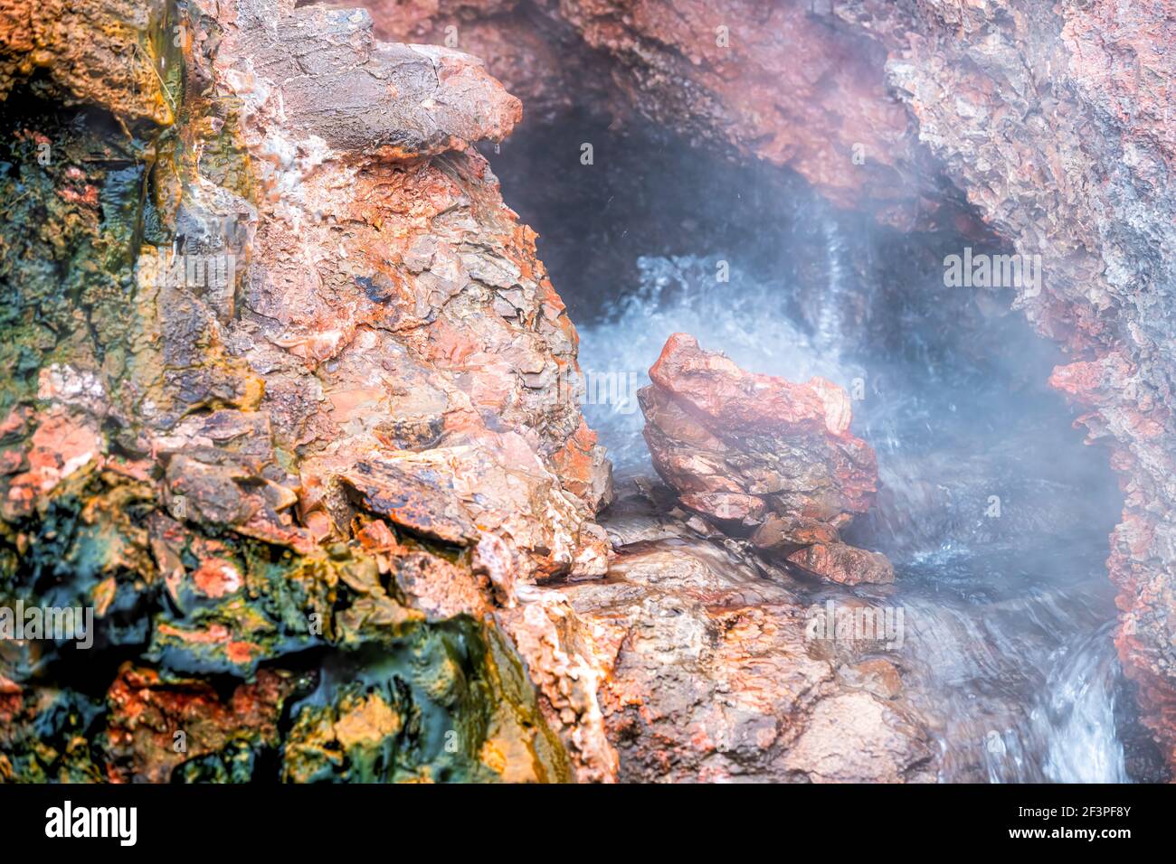 Gros plan de la vapeur longue exposition geyser dans Deildartunguhver chaud Printemps en Islande avec roche rouge coloré grotte trou d'ouverture et l'eau bouillante Banque D'Images