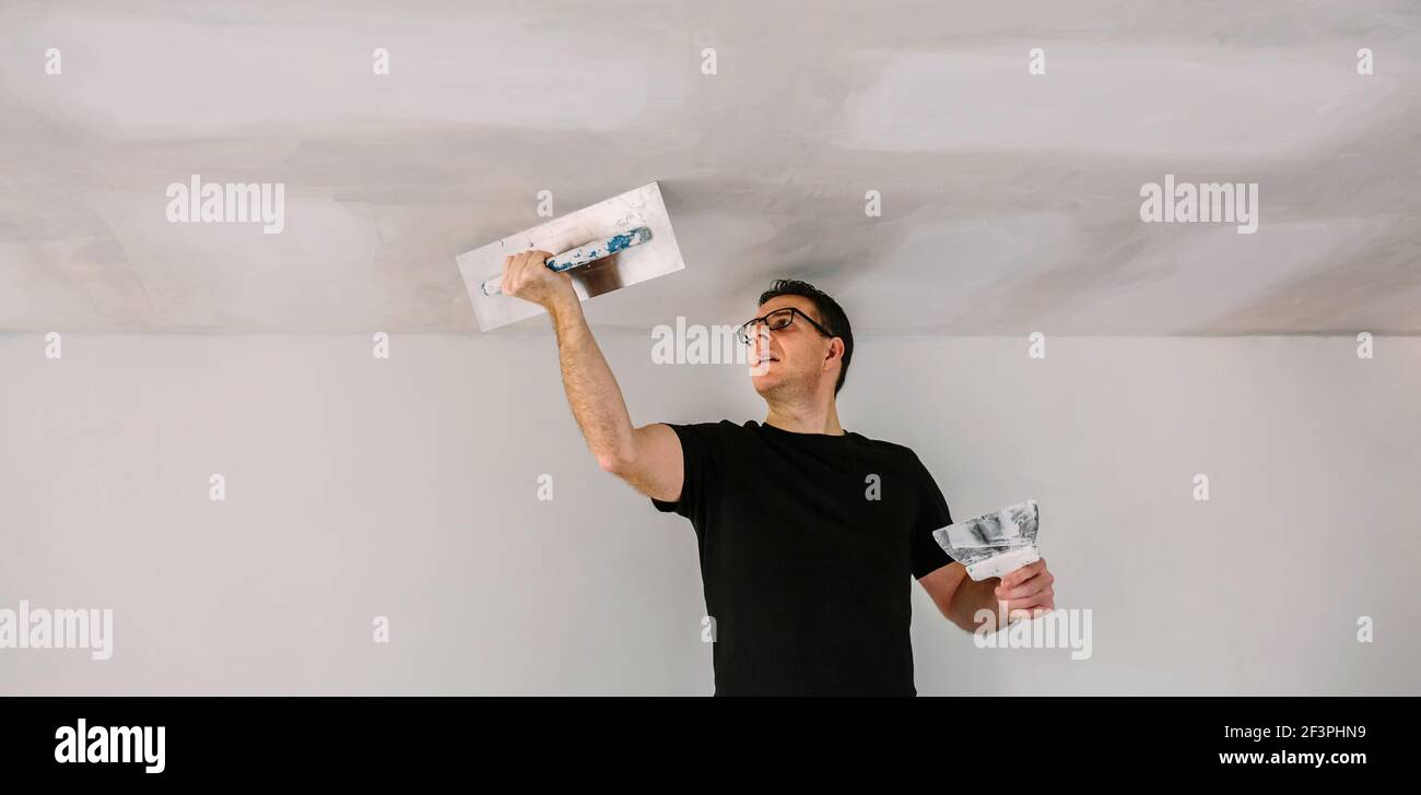 Plâtrier lissant le plafond en plâtre avec la truelle Banque D'Images