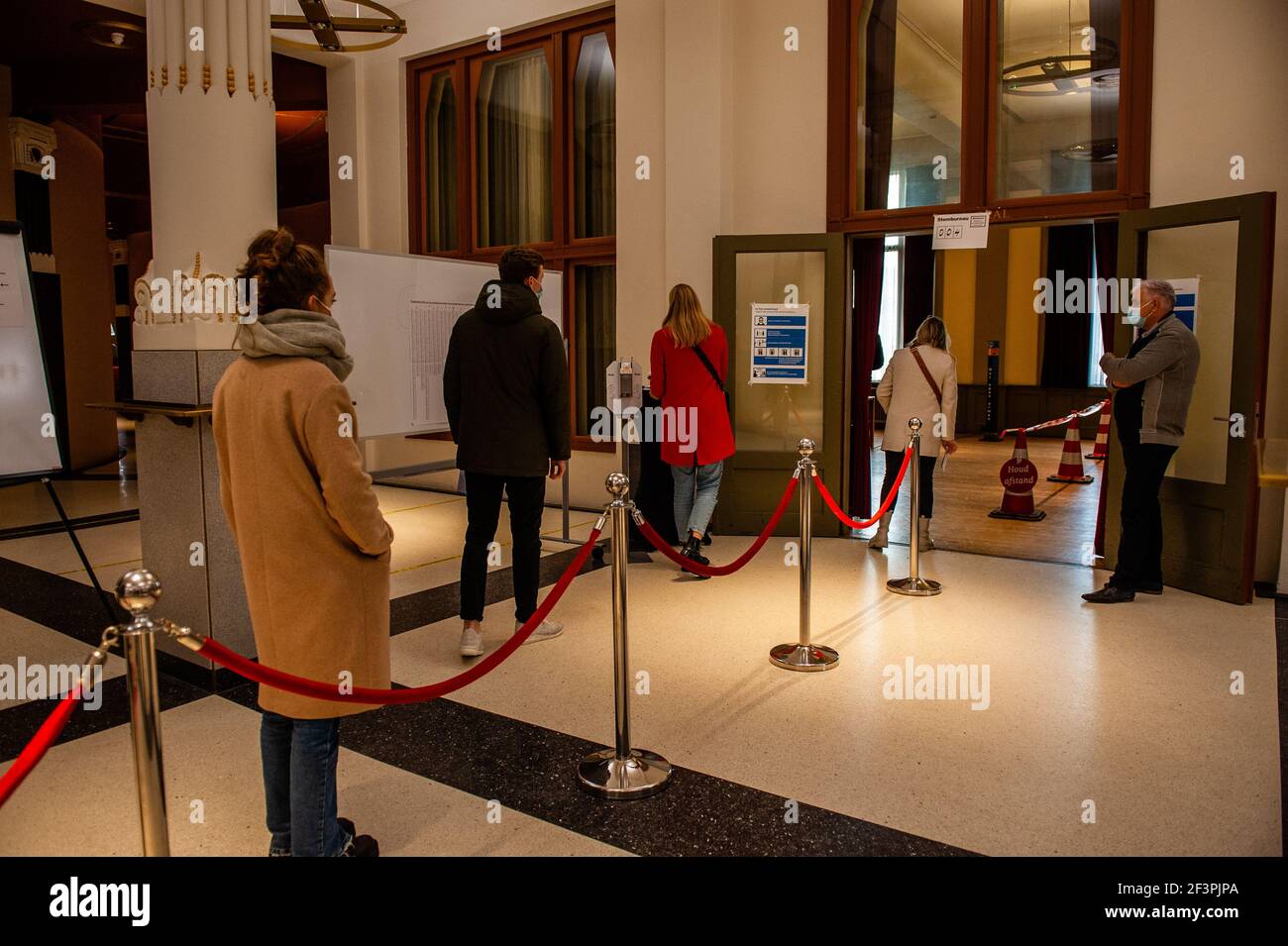 Les gens qui attendent de se jeter dans la file d'attente pour leur vote.Netherlands est l'un des pays à organiser des élections générales en 2021 dans le cadre du confinement du coronavirus. Pour réduire le risque de contamination, le gouvernement a pris des mesures de protection contre les corona, telles que l'ouverture de bureaux de vote dans différents endroits comme des églises, des gares, des salles de concert, ainsi que l'installation de systèmes univoies et d'écrans en plastique. L'un des problèmes les plus épineux s'est avéré être le crayon rouge emblématique que chaque électeur hollandais utilise pour marquer son choix. Banque D'Images