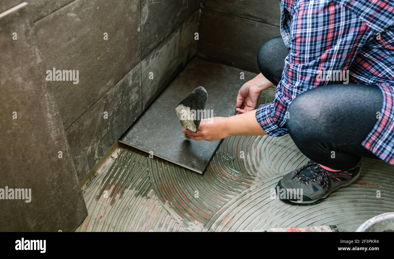 Femme ouvrier posant un nouveau plancher de carrelage Banque D'Images
