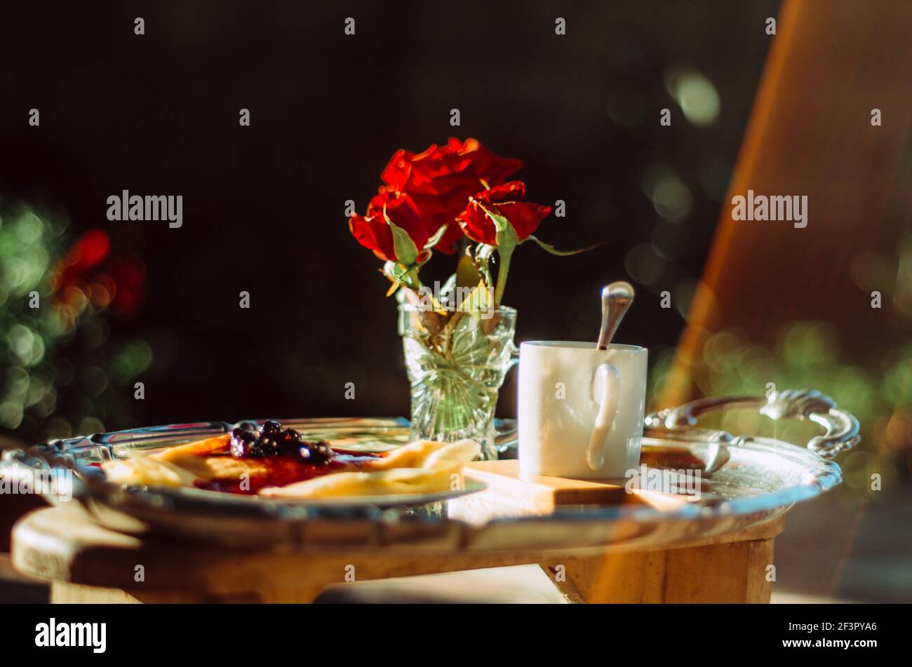 Brunch en plein air avec gros plan d'une tasse de café expresso et crêpes avec confiture, et roses dans un verre sur un plateau argenté vintage Banque D'Images