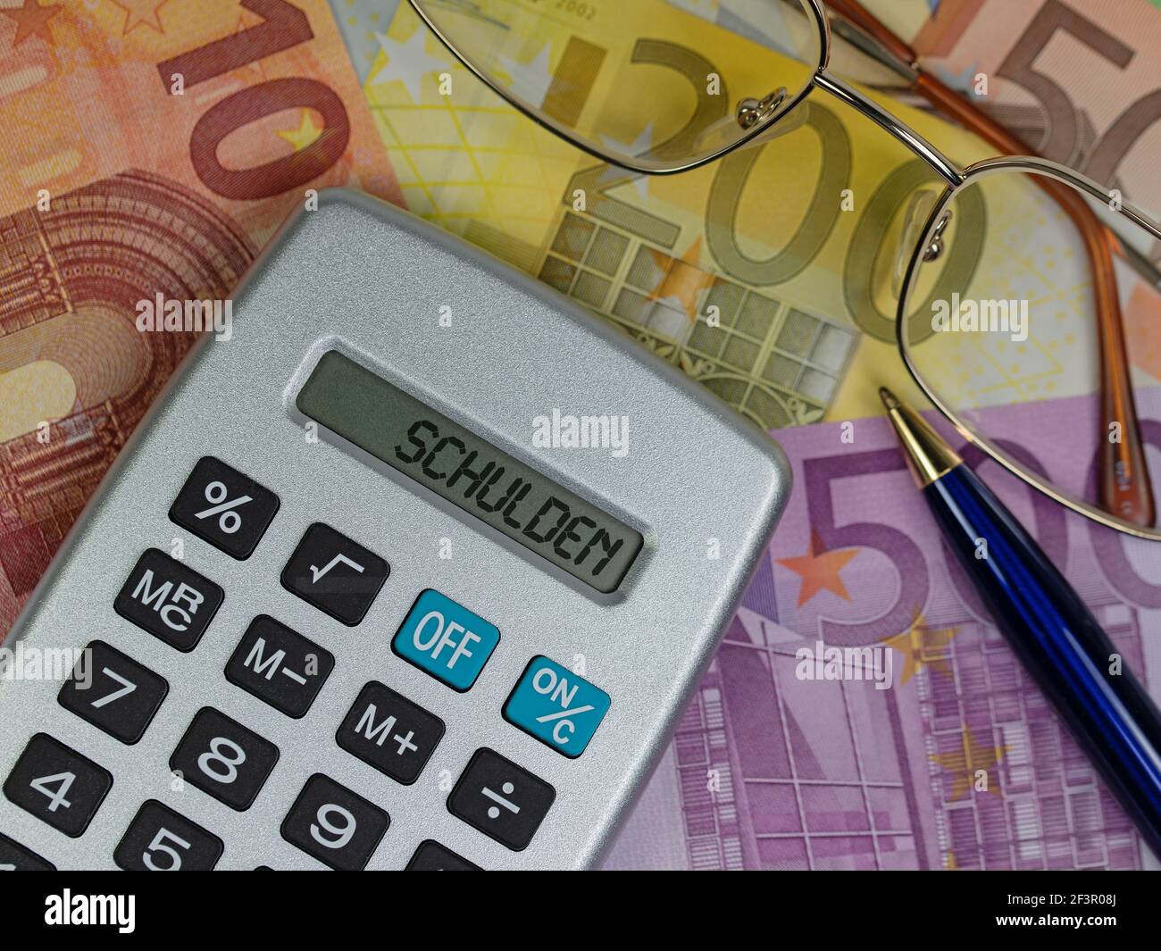Calculatrice de poche avec le texte « Schulden » sur les factures, traduction « debt » Banque D'Images