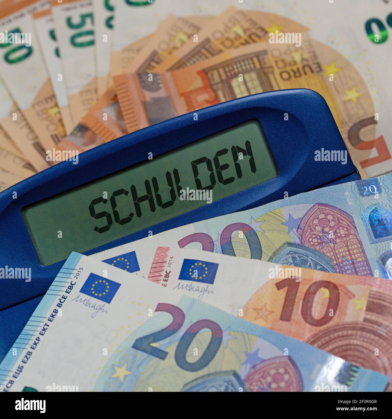 Calculatrice de poche avec le texte « Schulden » sur les factures, traduction « debt » Banque D'Images