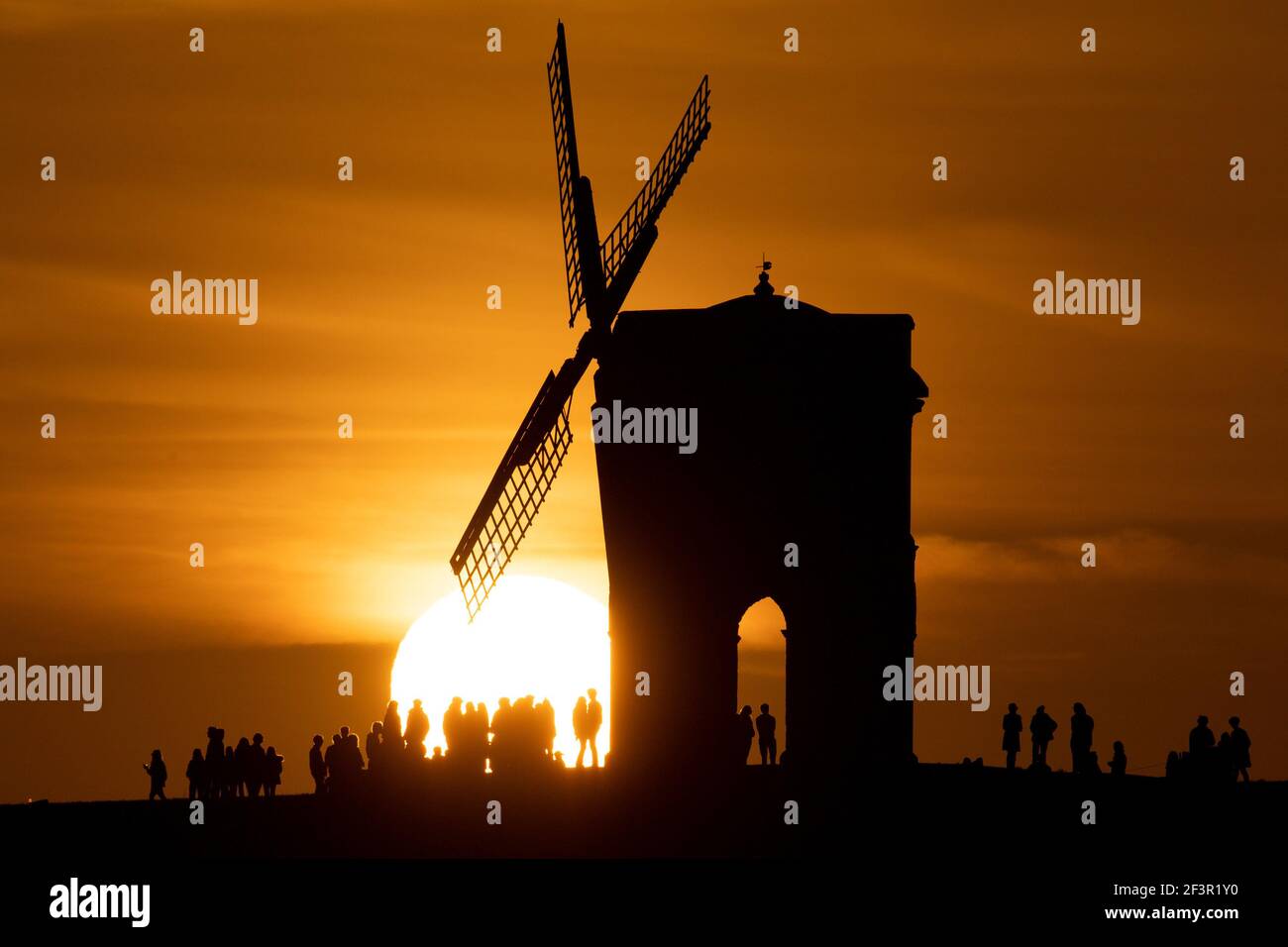 Des groupes de personnes regardent le coucher du soleil par le Moulin à vent de Chesterton dans le Warwickshire. Date de la photo: Mercredi 17 mars 2021. Banque D'Images