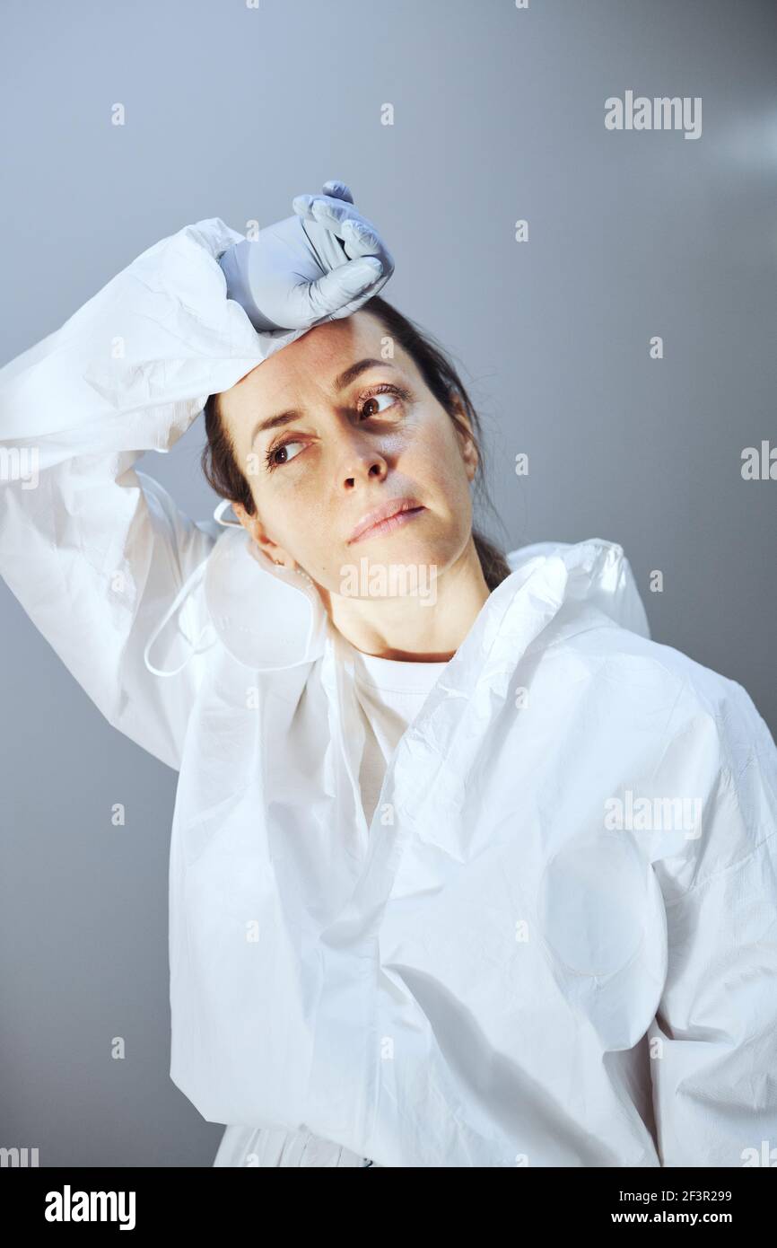 Femme fatiguée médecin en uniforme de protection debout dans le couloir de l'hôpital Banque D'Images