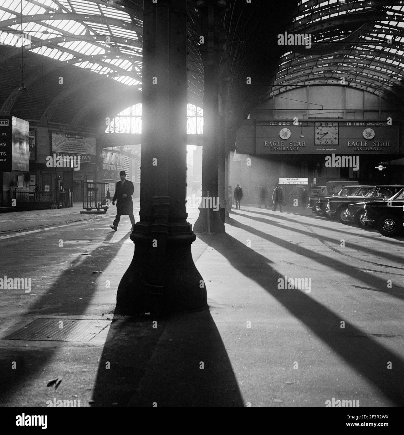 GARE DE PADDINGTON, Londres. Intérieur de la gare de Paddington au premier feu avec un passager passant devant de grandes colonnes vers les plates-formes d'un A. Banque D'Images