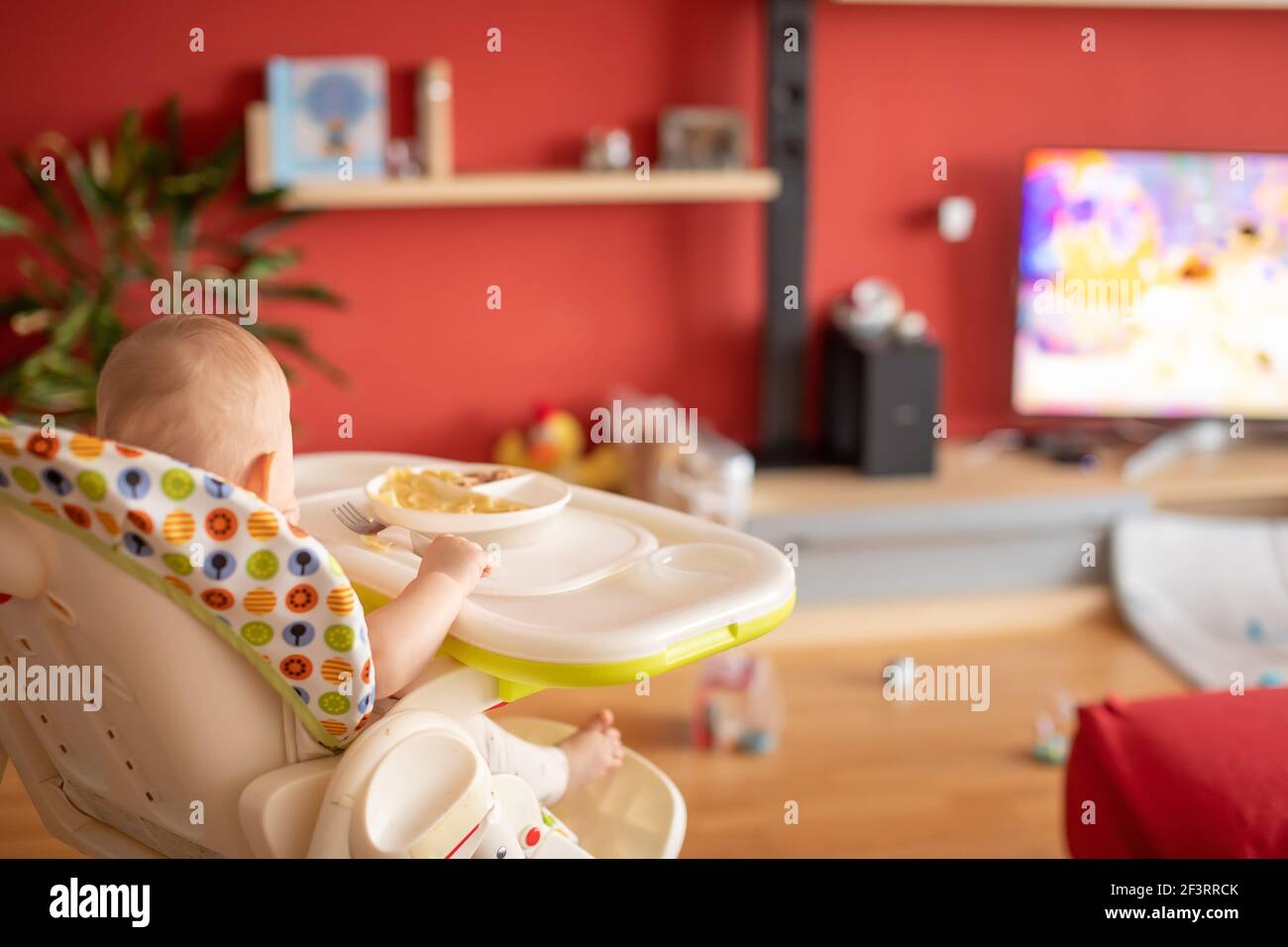 Bébé fille regardant des dessins animés à la télévision et manger un repas équilibré Banque D'Images