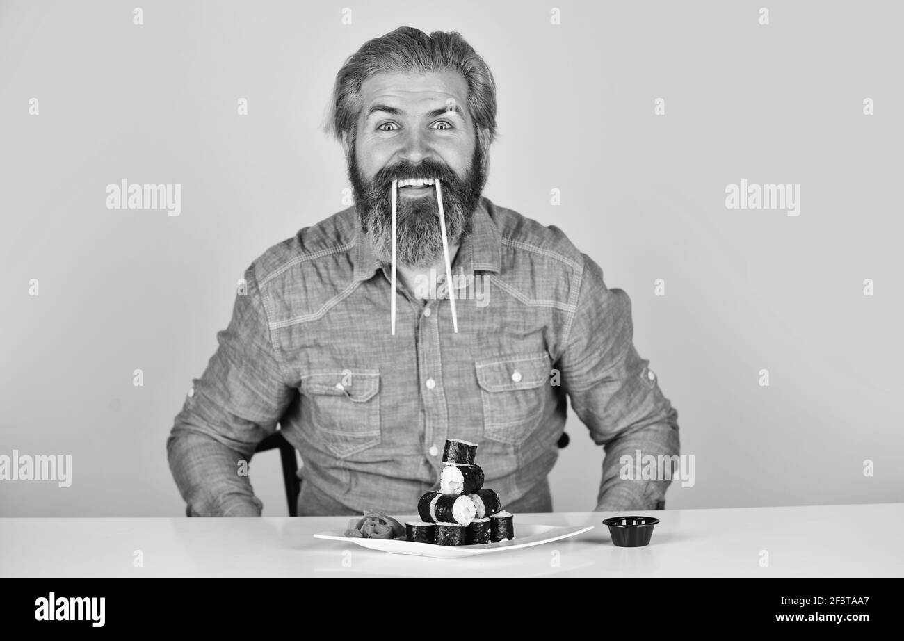 Plat à sushis japonais. Homme mangeant de la nourriture japonaise traditionnelle avec des baguettes. Dîner à la maison. sushi à manger avec des baguettes. Délicieux rouleau à sushis Banque D'Images