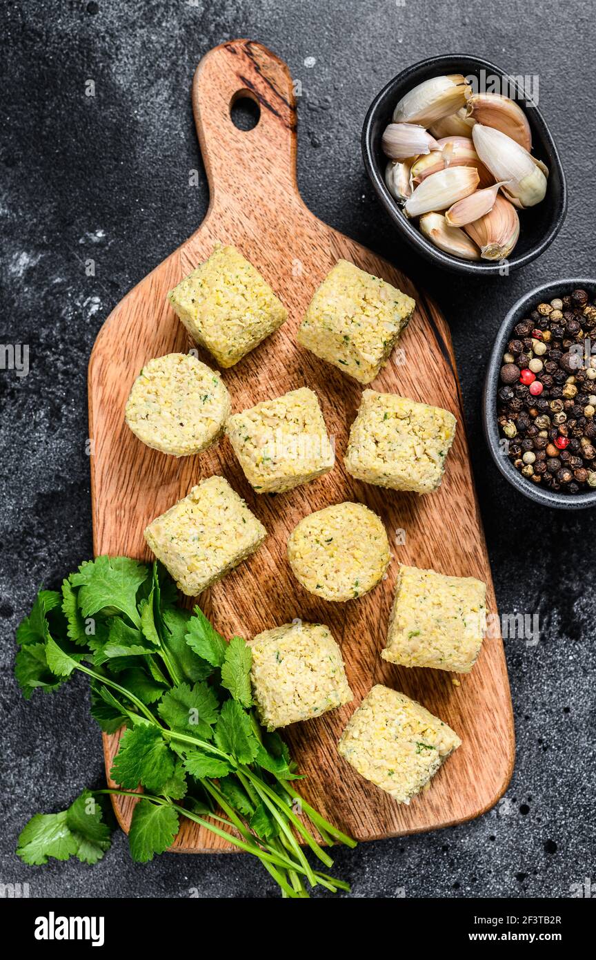 Billes de falafel brutes sur une planche à découper en bois. Arrière-plan noir. Vue de dessus Banque D'Images